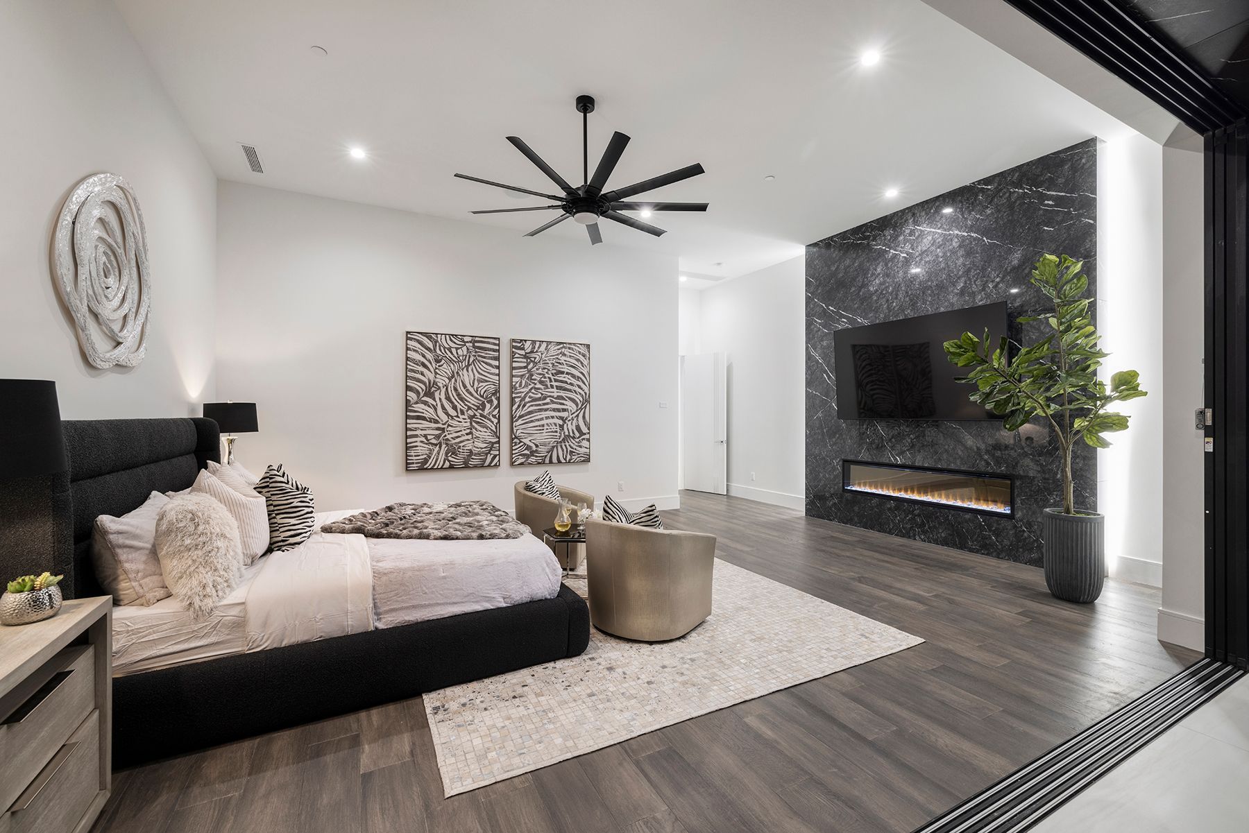 a bedroom with a large bed, ceiling fan, television and fireplace