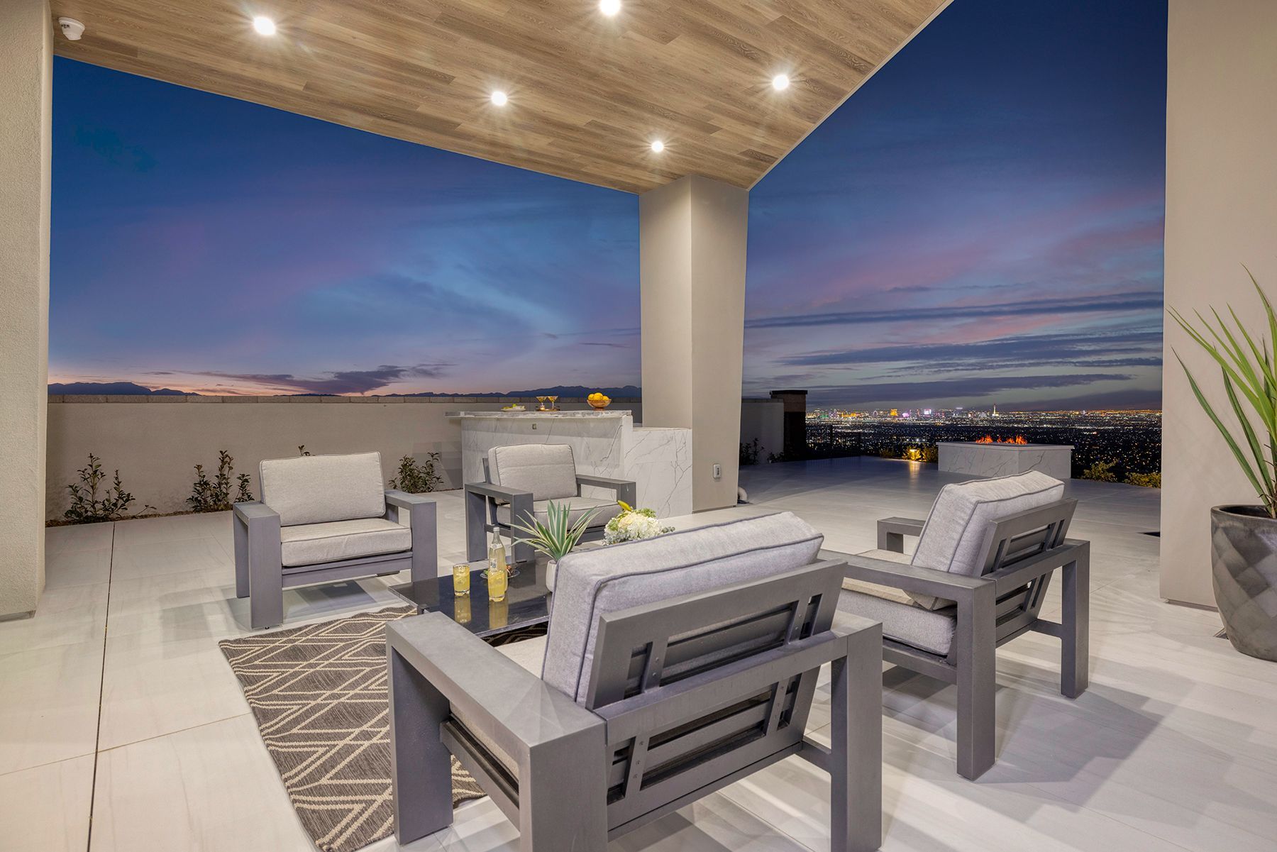 a patio with chairs and a table with a view of the city at night