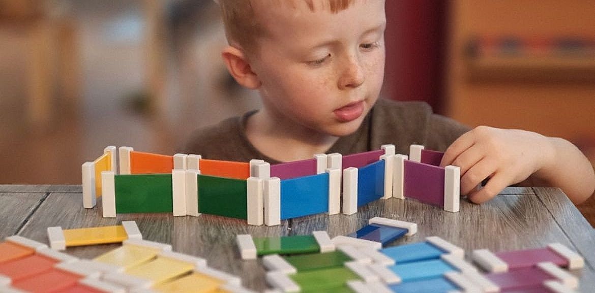 A child playing with colorful blocks, arranging them on a table. The blocks are in a variety of colors.