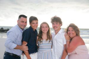 A family is posing for a picture on the beach.