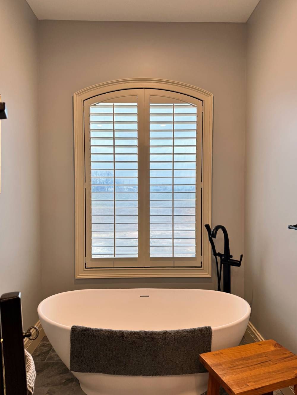 A bathroom with a bathtub and a window with shutters.