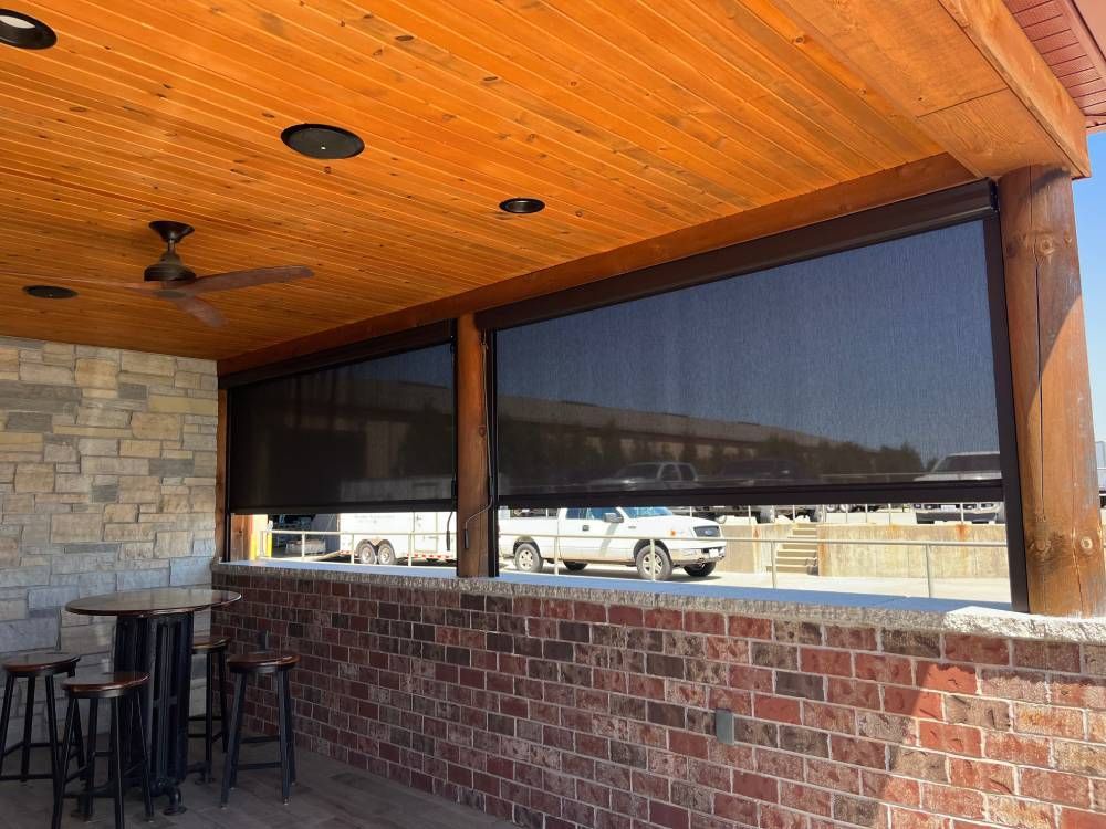 A patio with a wooden ceiling and a brick wall.