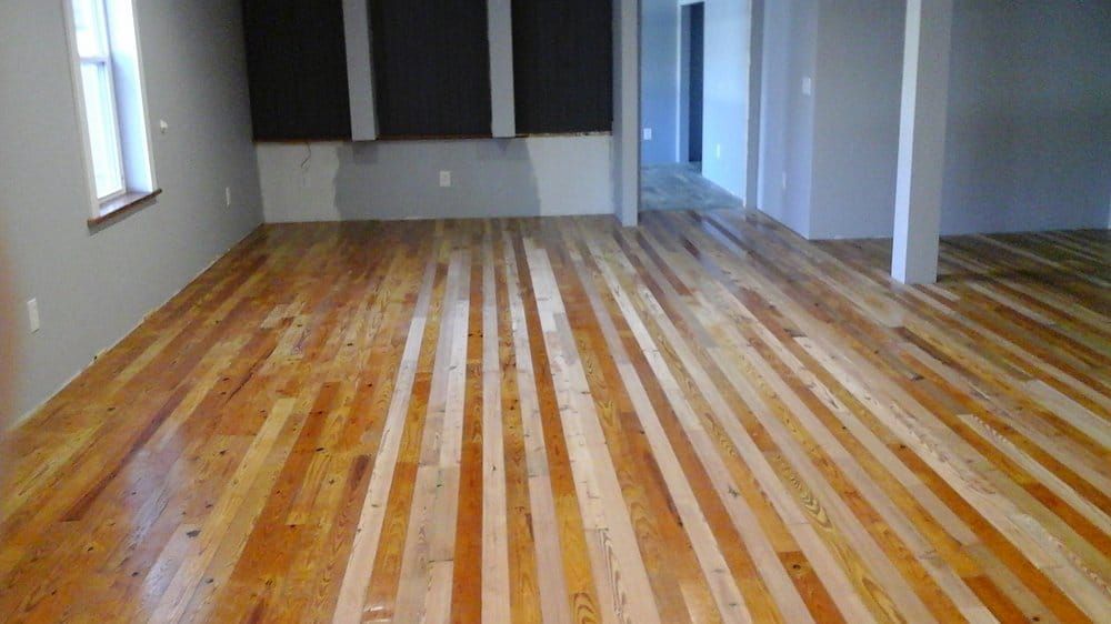 A room with newly installed, multi-toned light and dark wooden plank flooring throughout an open living area.
