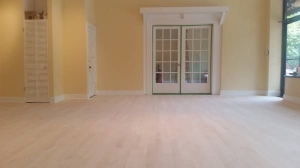 An empty room with pale wood floors, light yellow walls, a set of French doors, and a louvered closet door.