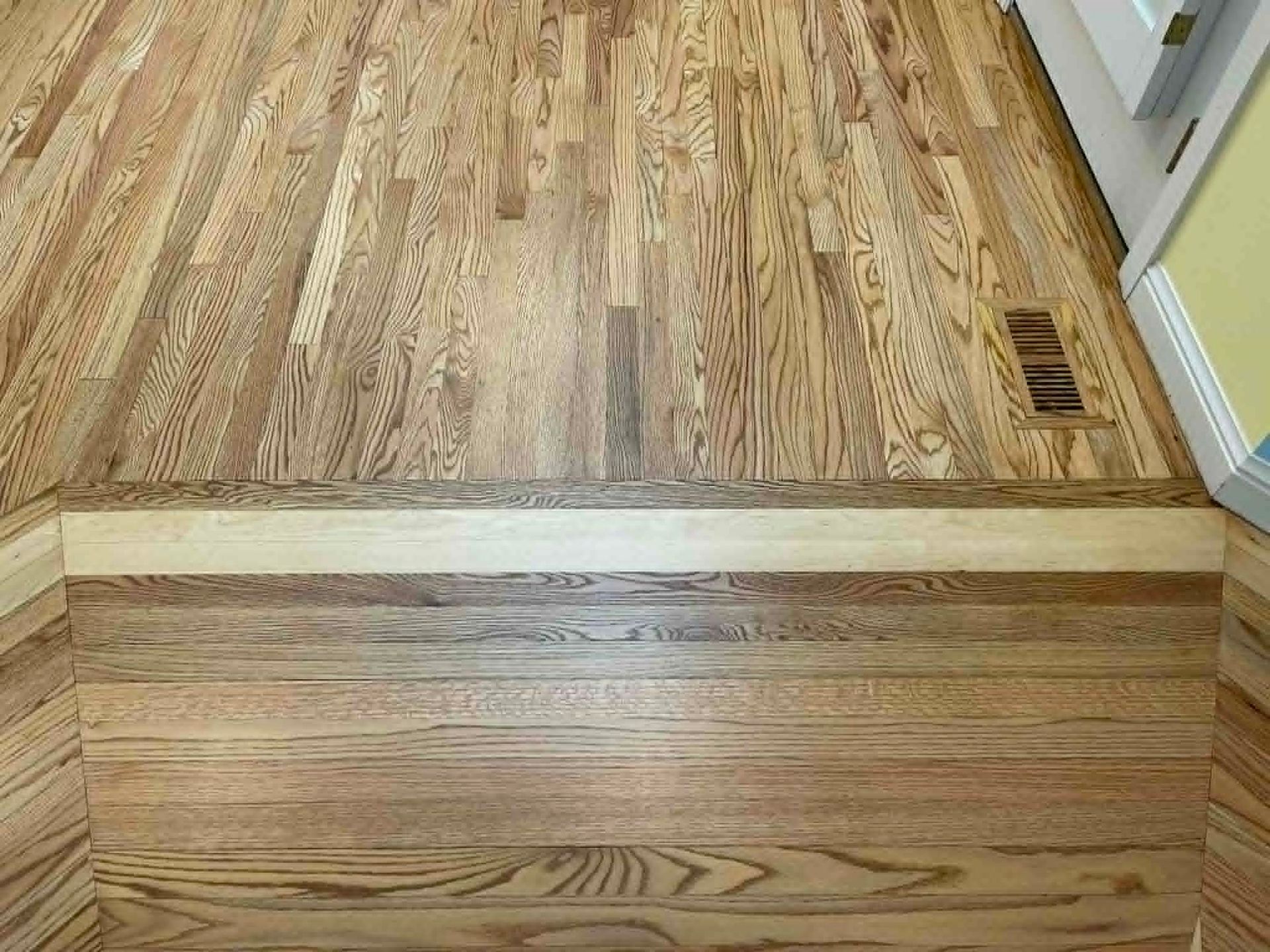 Wood floor transitioning to a raised hardwood threshold between rooms