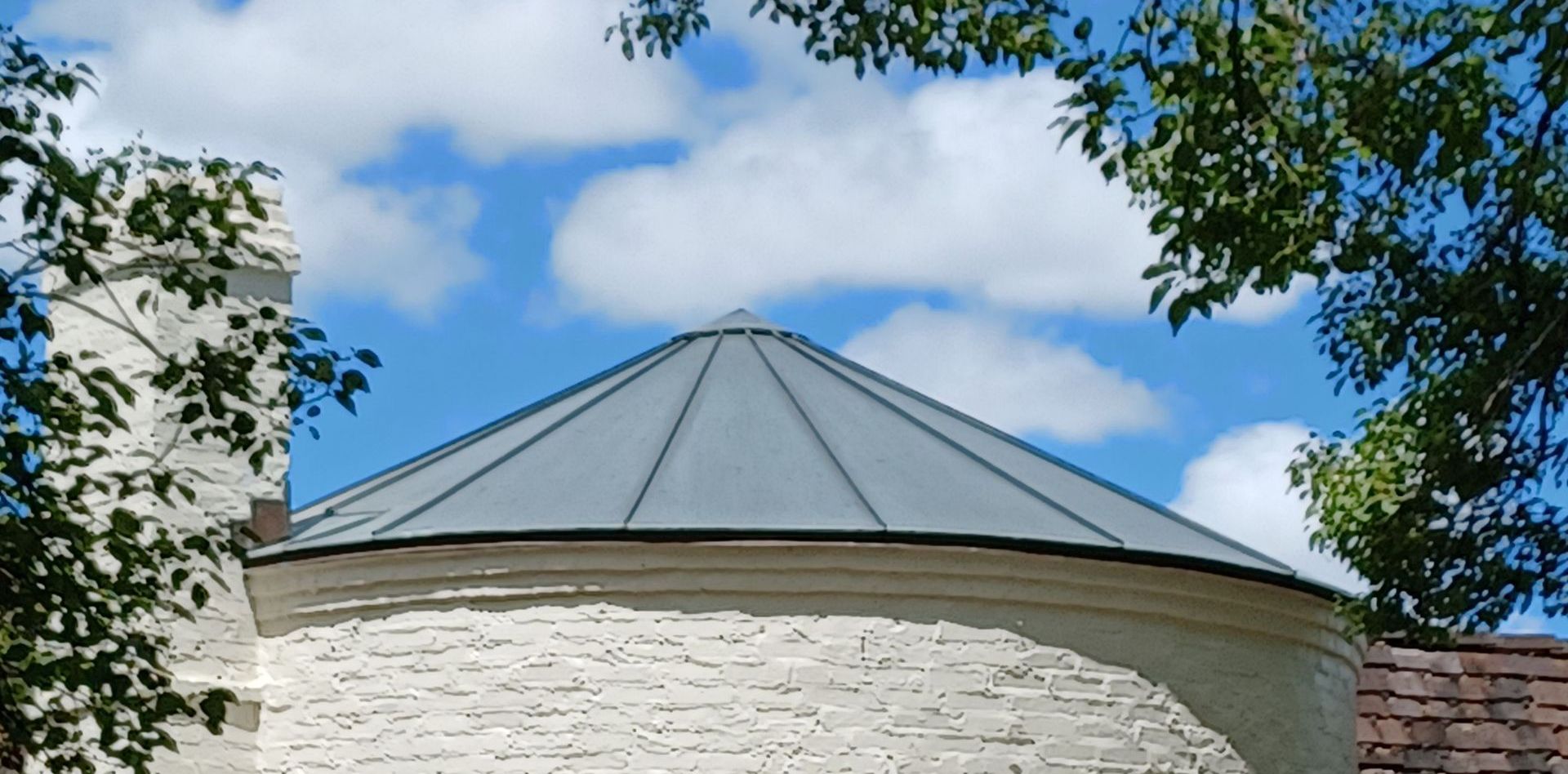A white brick building with a metal roof and a chimney