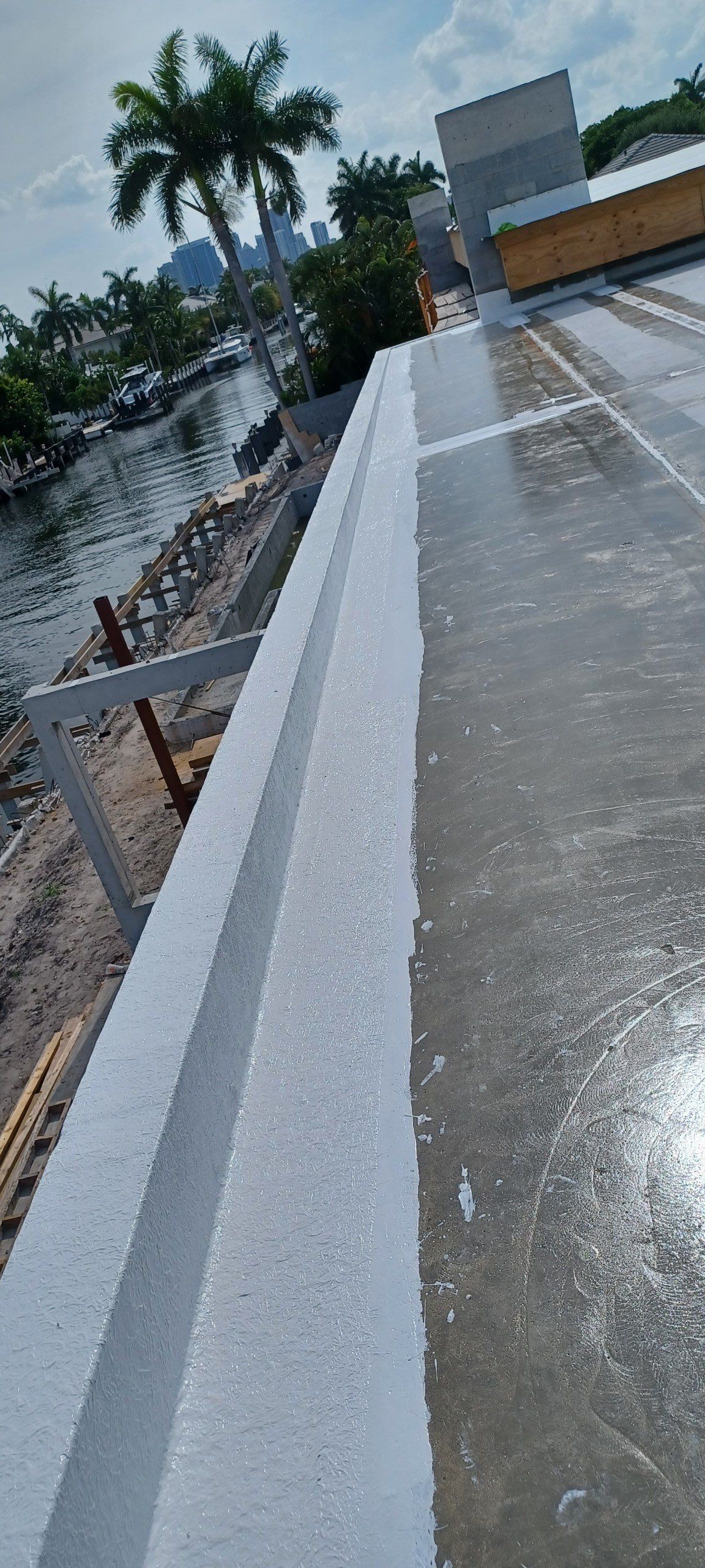 A white railing is sitting on top of a concrete surface next to a body of water.