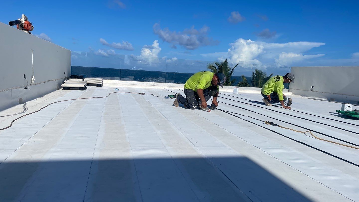 A group of men are working on a white roof.