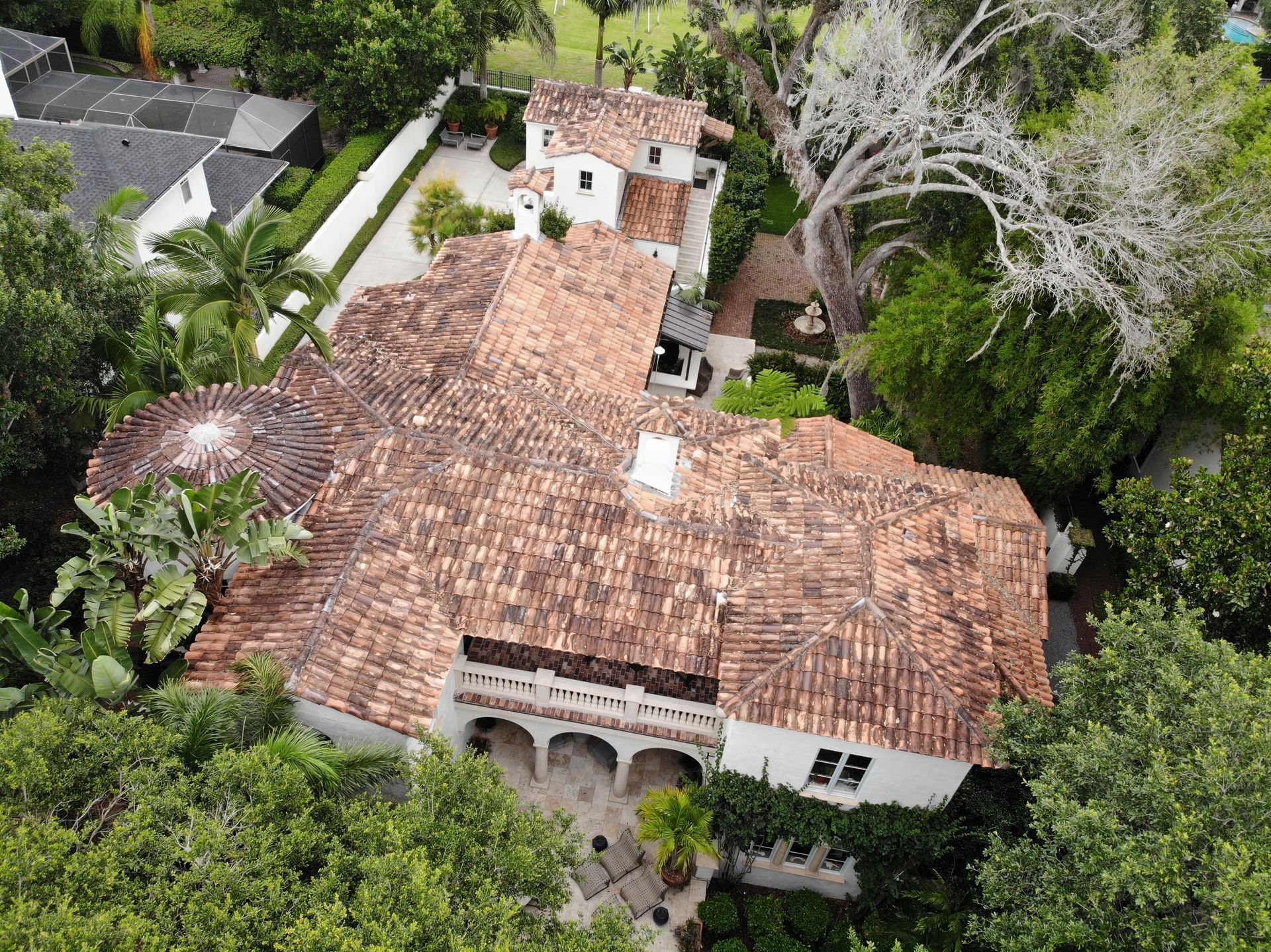 An aerial view of a large house with a tiled roof surrounded by trees.