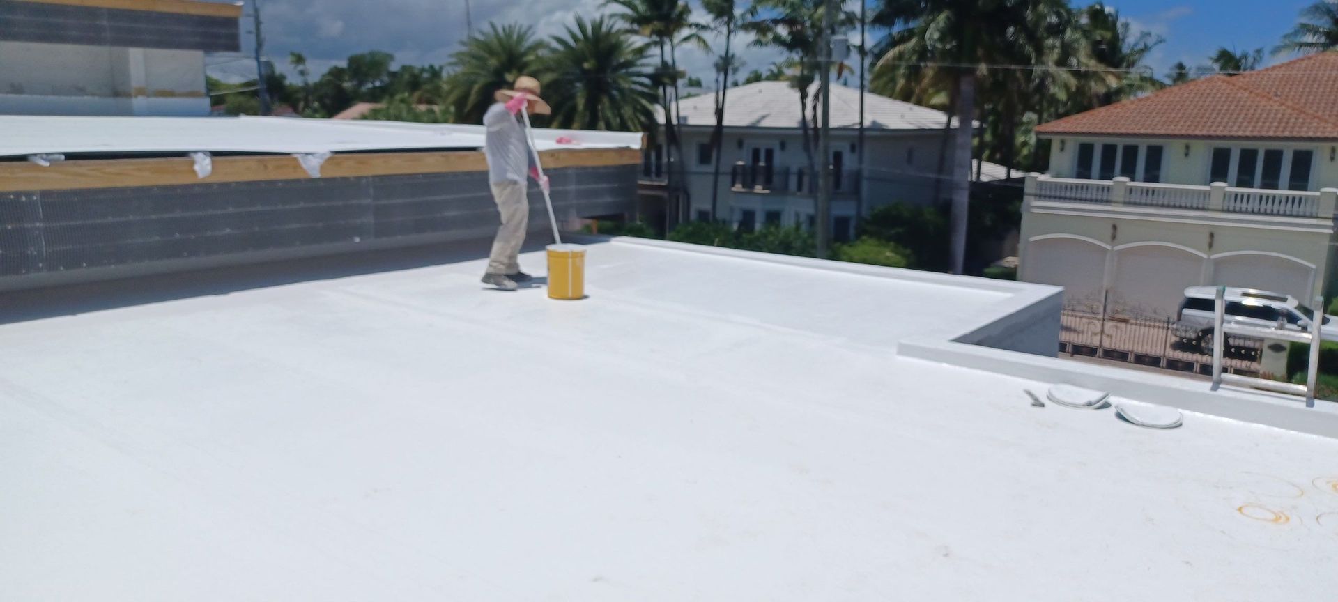 A man is painting a roof with a bucket.