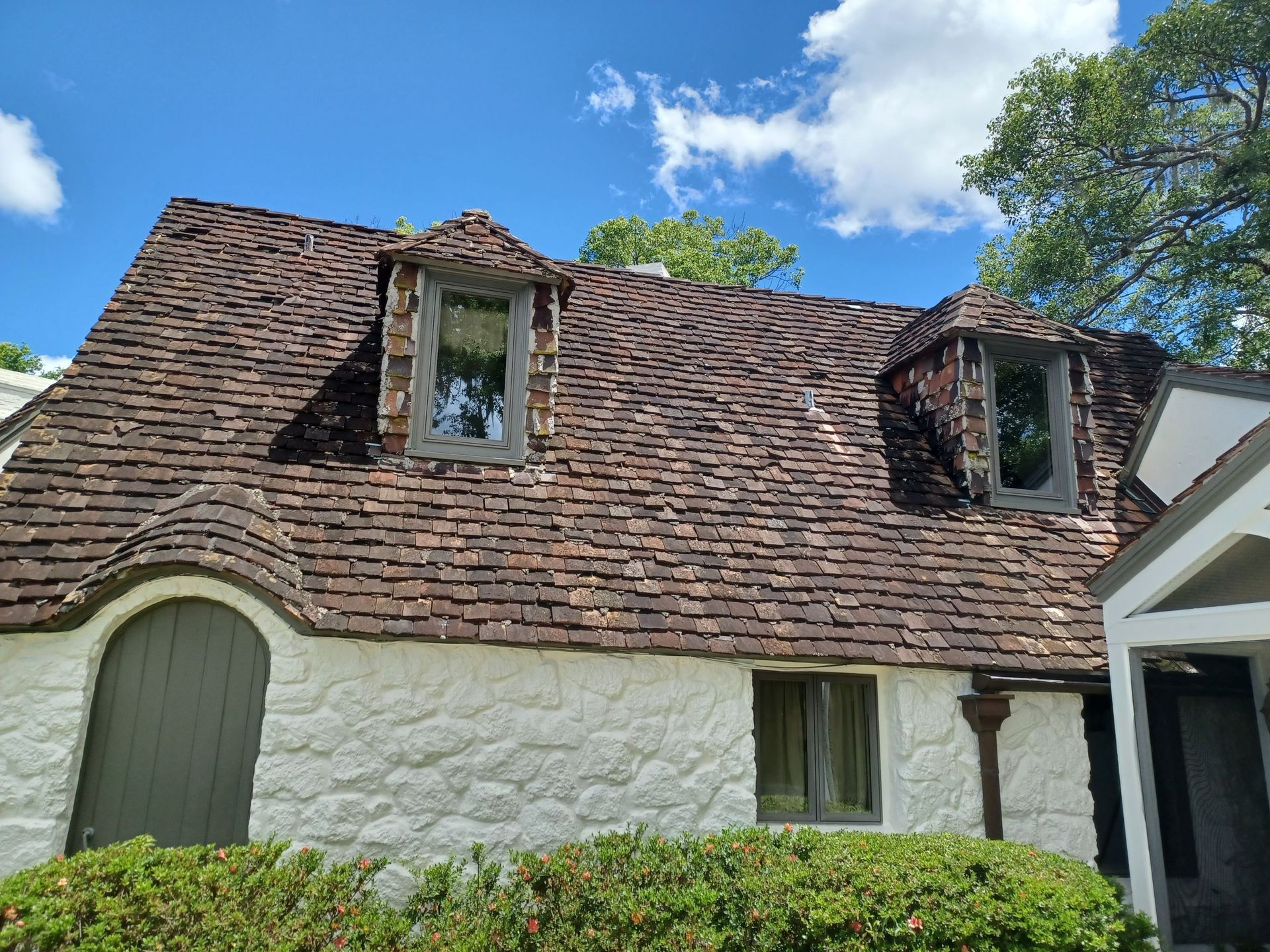 A white house with a brown roof and two windows.