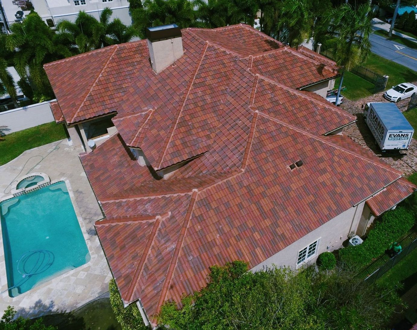 An aerial view of a house with a red tile roof and a pool.