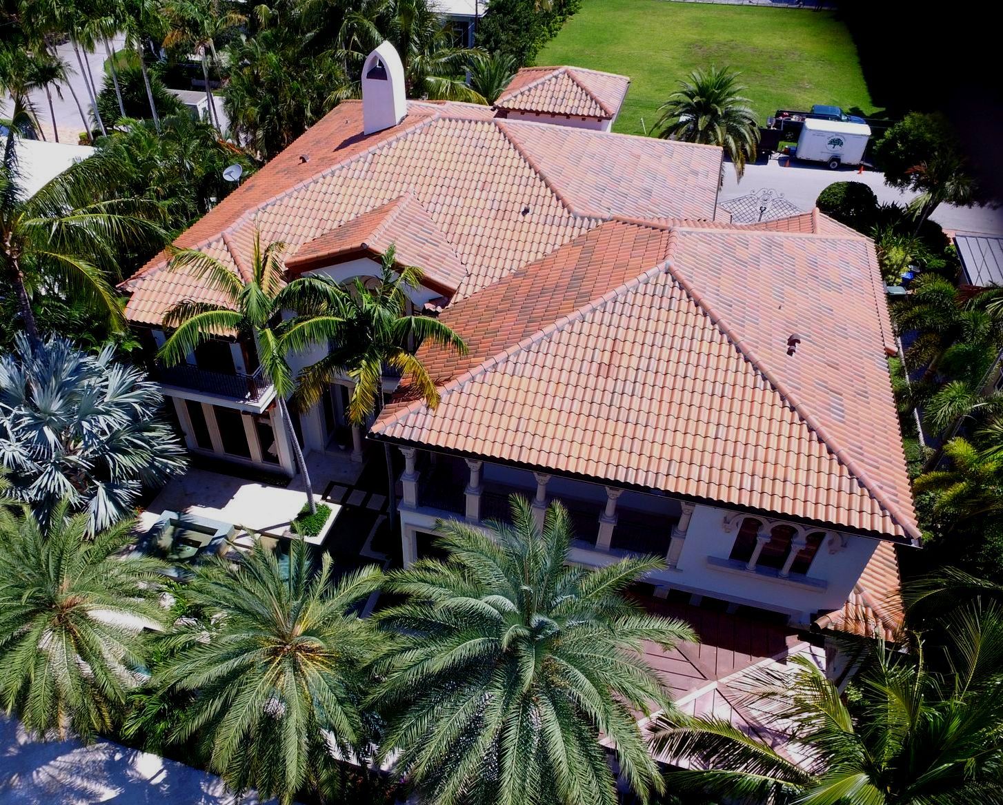 An aerial view of a large house surrounded by palm trees