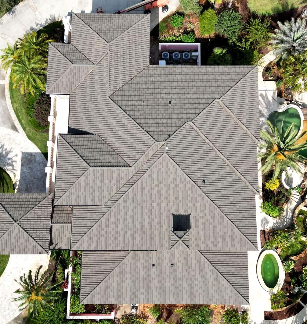 An aerial view of a large house surrounded by palm trees.