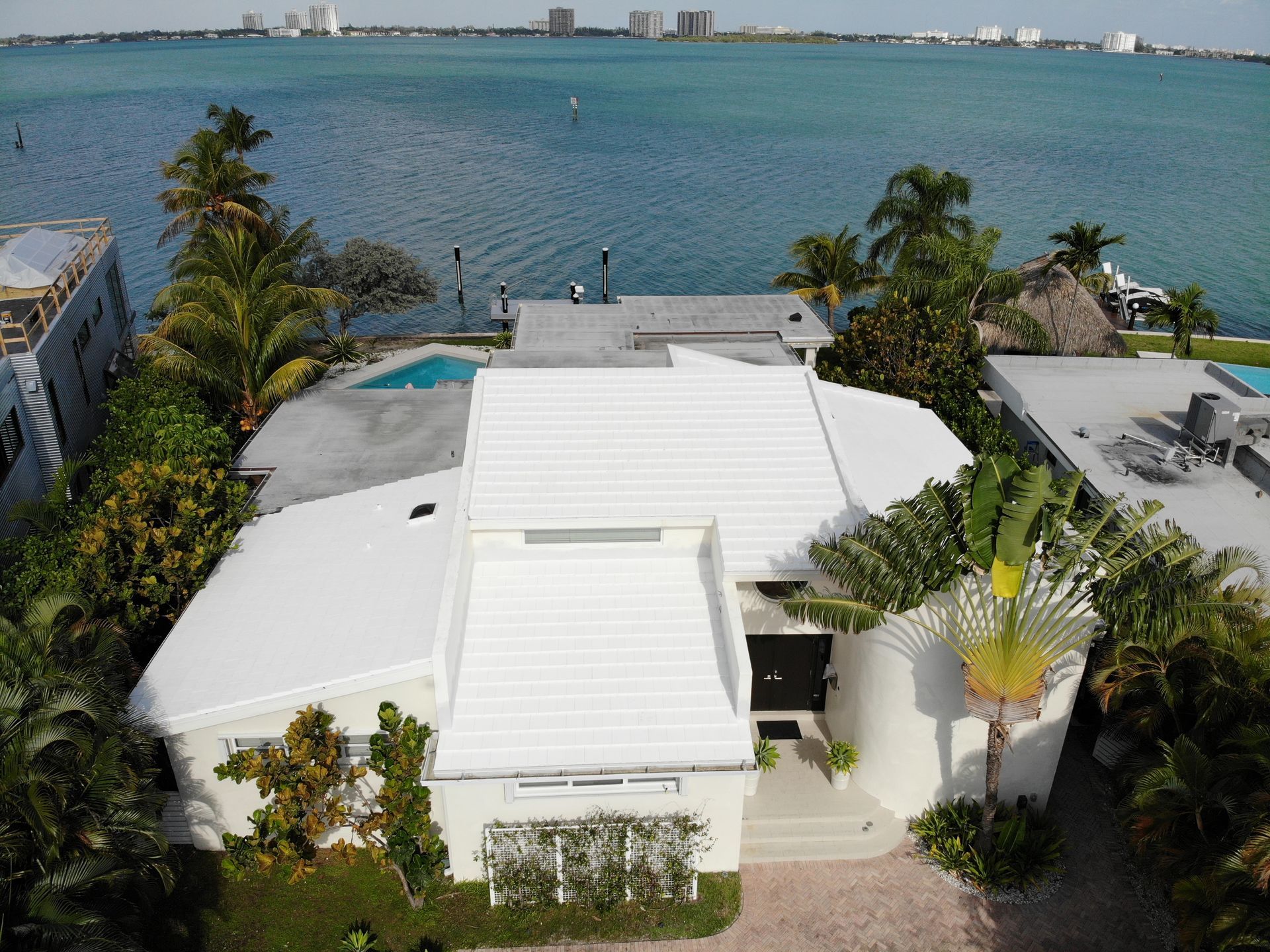 An aerial view of a white house next to a body of water