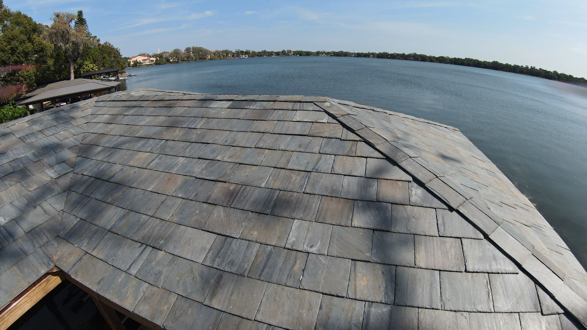 A roof overlooking a body of water with trees in the background
