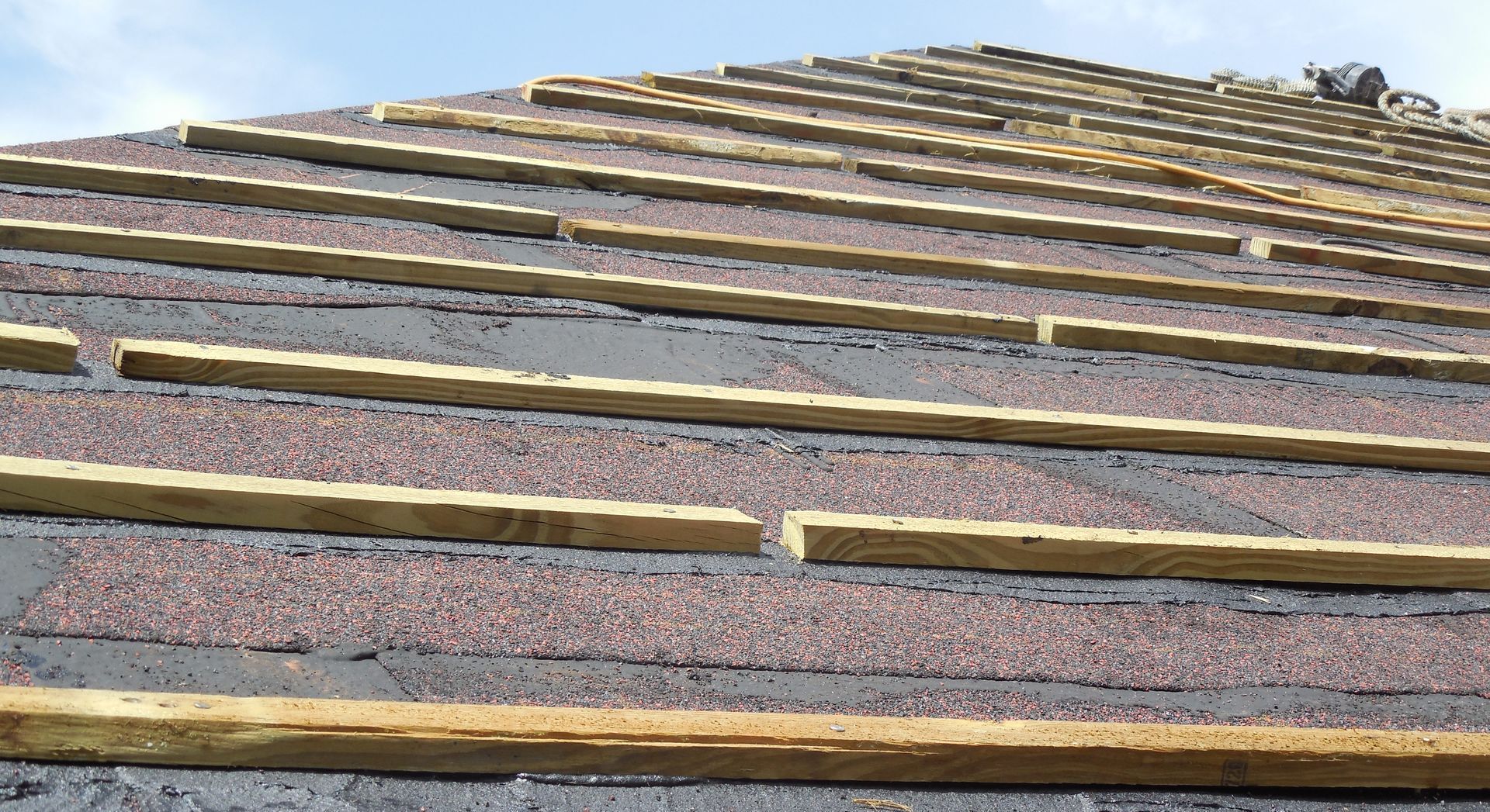 A roof is being built with wooden beams and shingles.