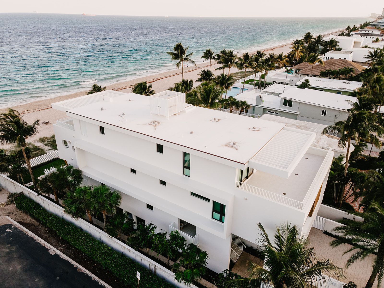 An aerial view of a large white house next to the ocean.