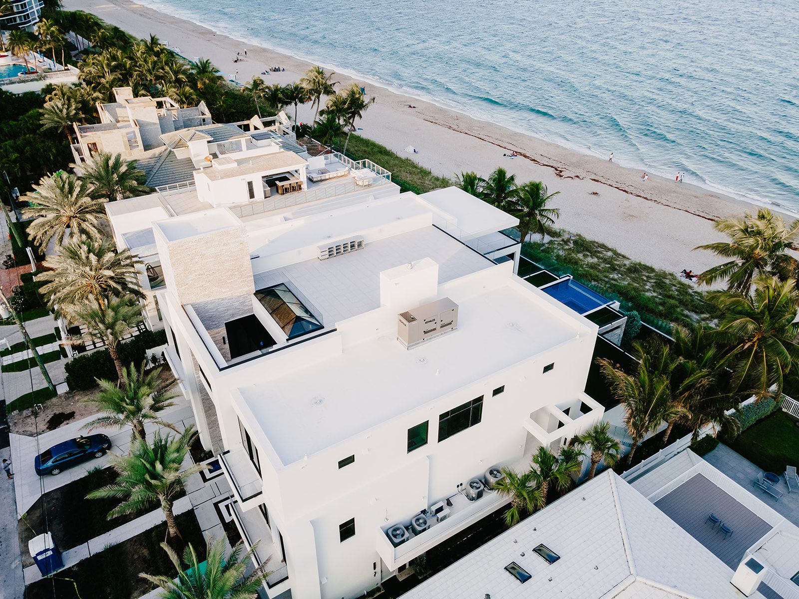 An aerial view of a large white house next to the ocean.