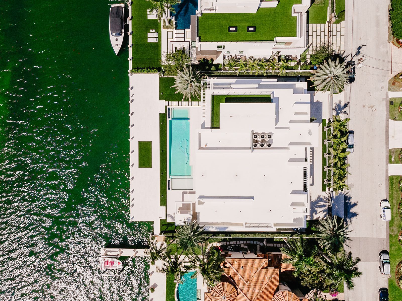 An aerial view of a house with a pool and a boat in the water.