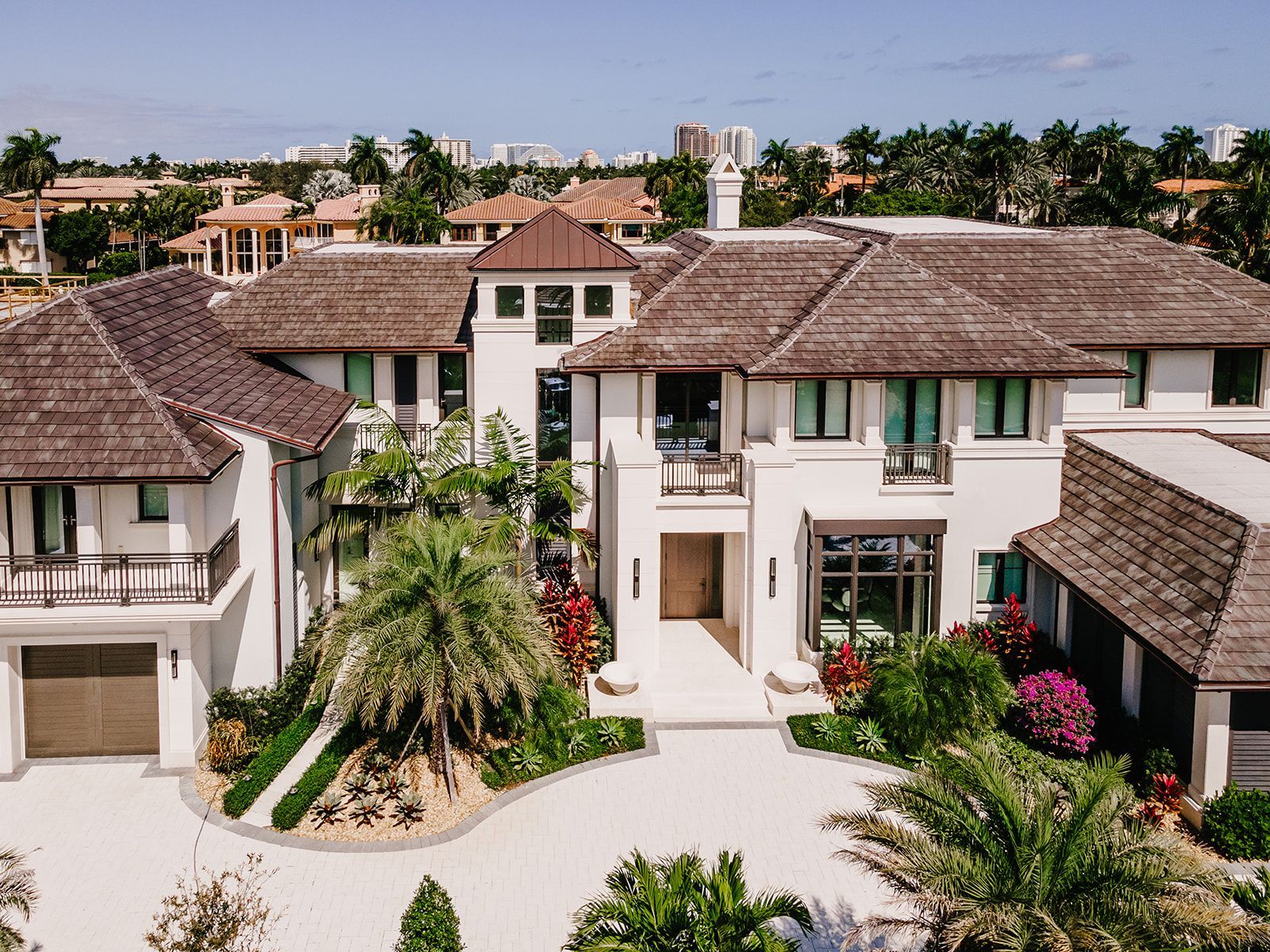 An aerial view of a large white house with a thatched roof surrounded by palm trees.