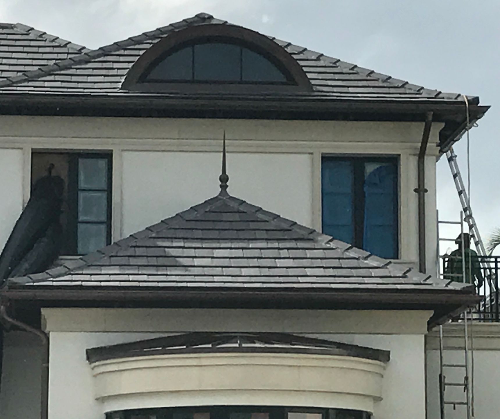 A white house with a brown roof and a round window