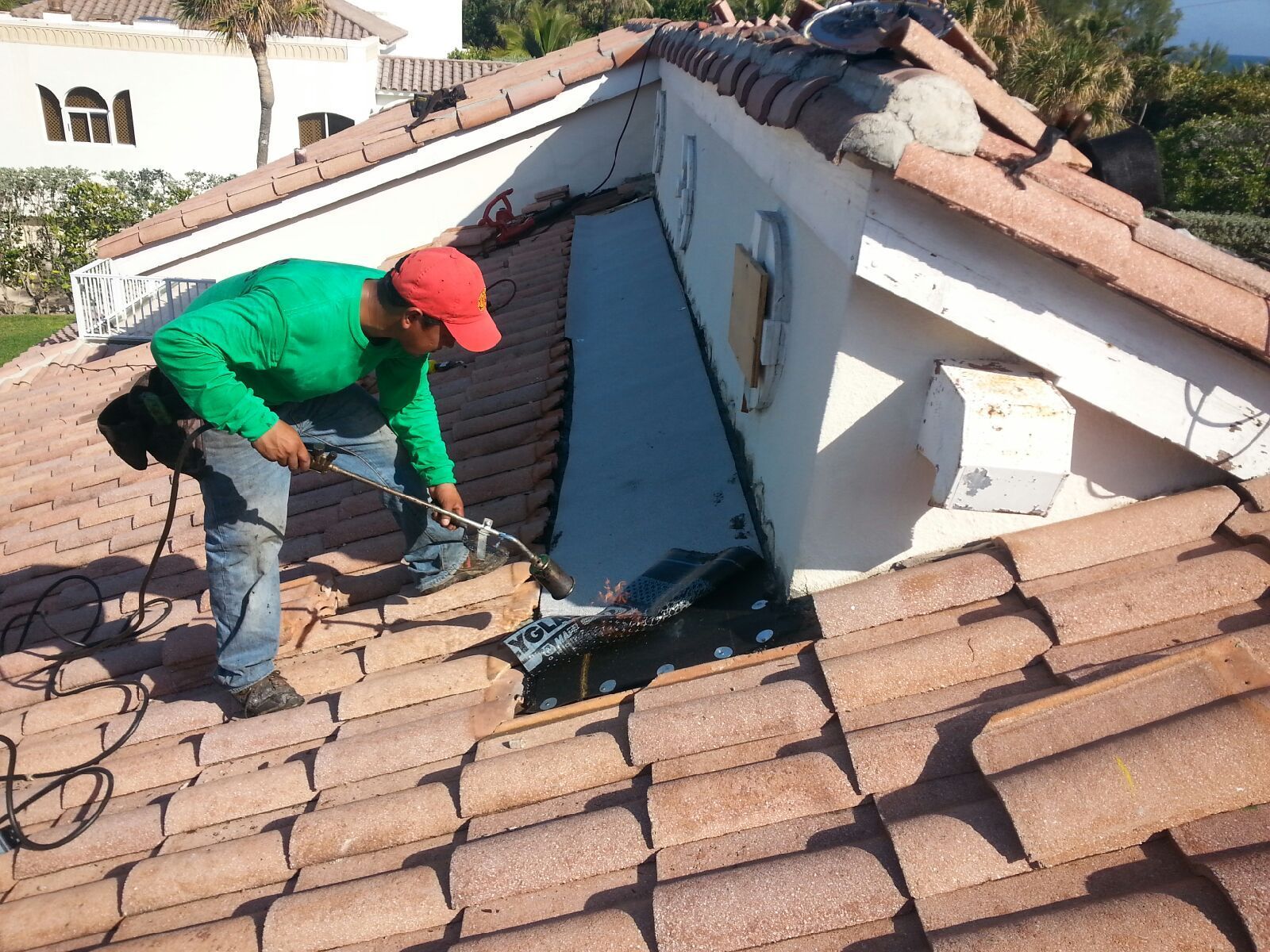 A man in a red hat is working on a tiled roof