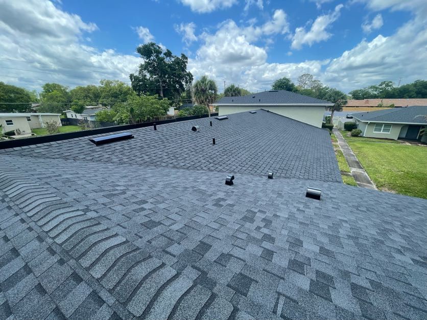 A roof with a lot of shingles on it and a house in the background.