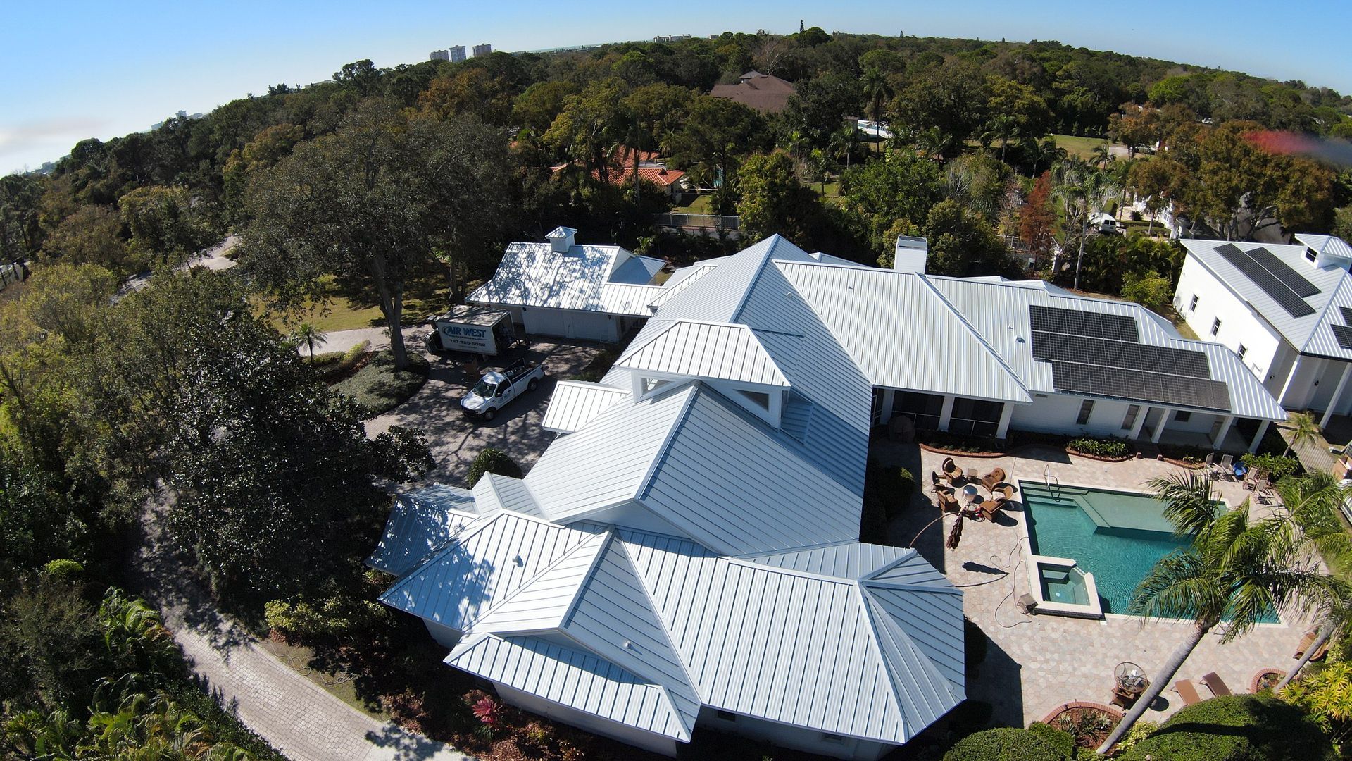 An aerial view of a large white house with a pool