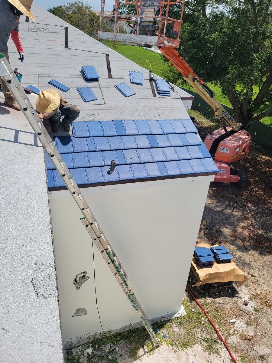 A man is standing on a ladder on the roof of a building.