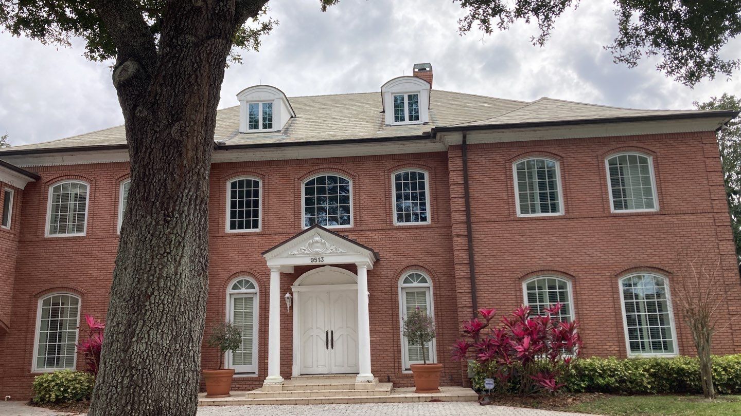 A large brick house with a tree in front of it.