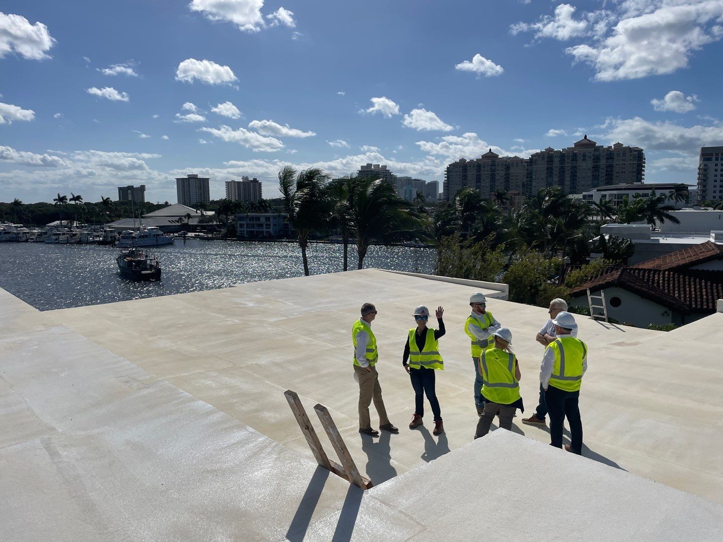 A group of construction workers are standing on top of a roof overlooking a body of water.
