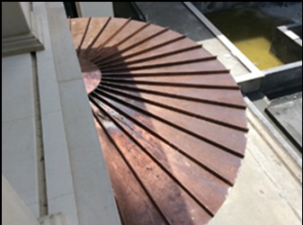 A copper umbrella is sitting on the side of a building