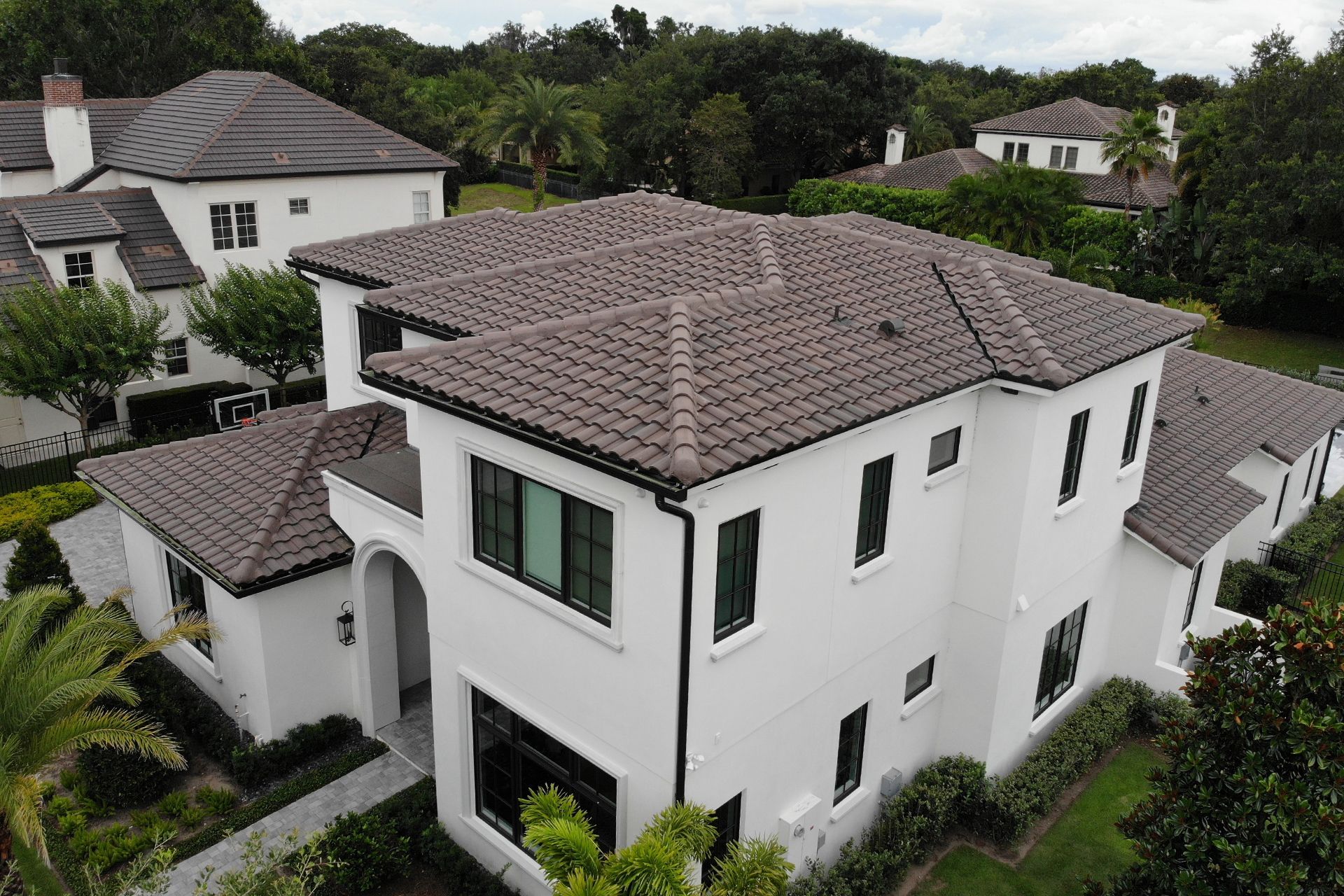 An aerial view of a large white house with a tile roof surrounded by trees.
