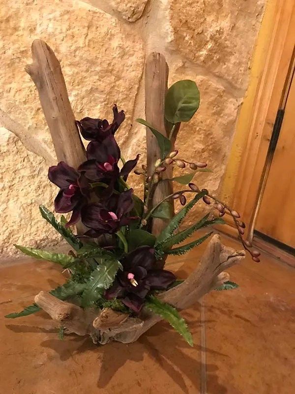 A vase filled with flowers and leaves is sitting on a table.