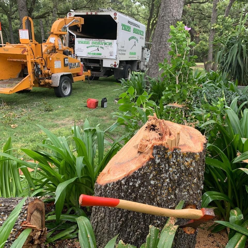 a stump among landscaping next to company truck and wood chipper