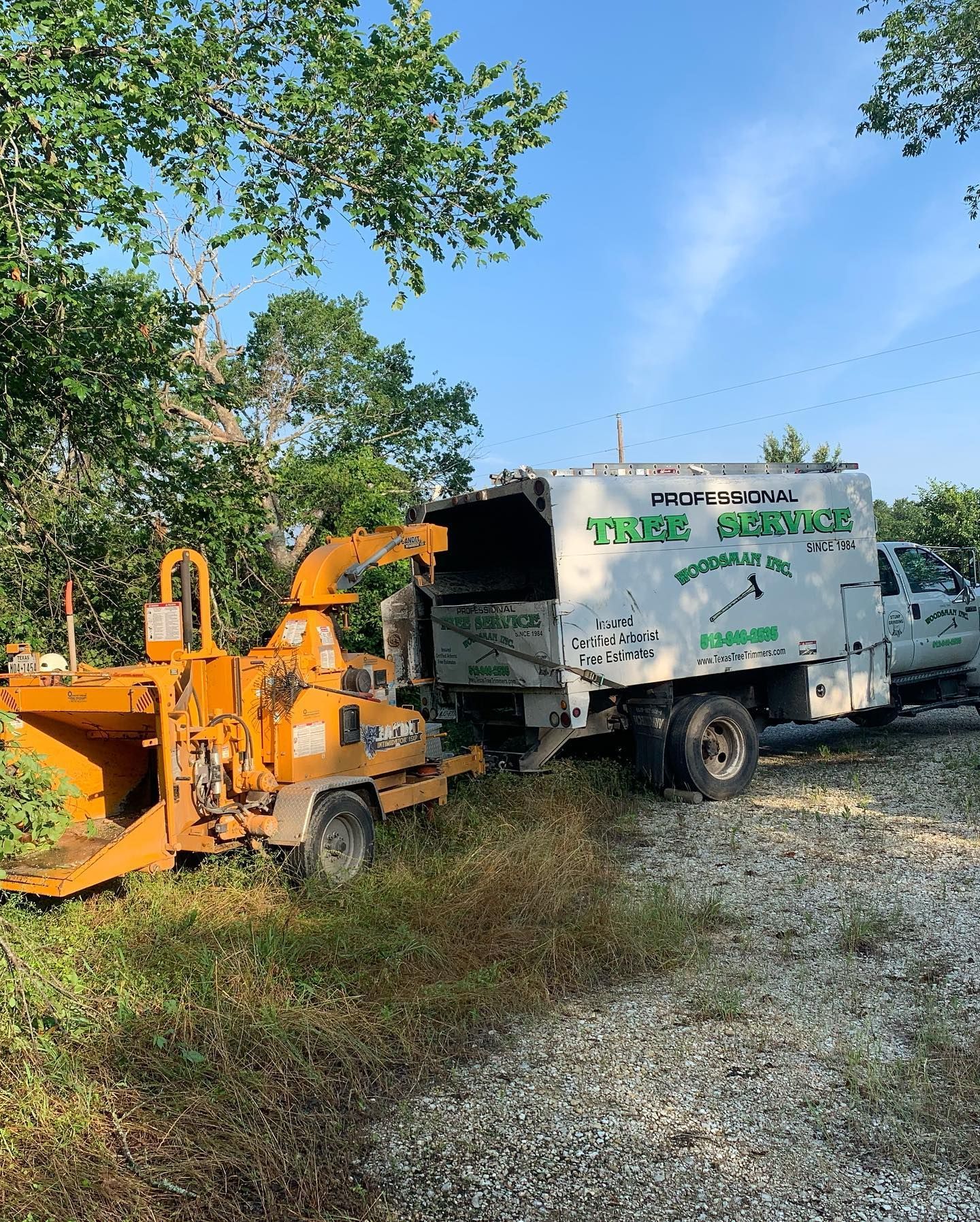 A tree chipper is parked next to a truck.