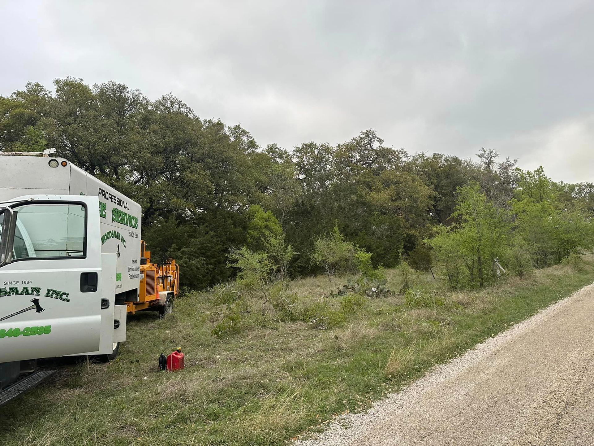 A white truck is parked on the side of a dirt road.