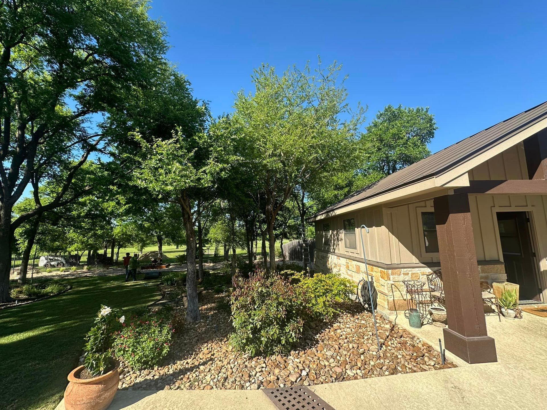 A house with a porch and trees in front of it on a sunny day.