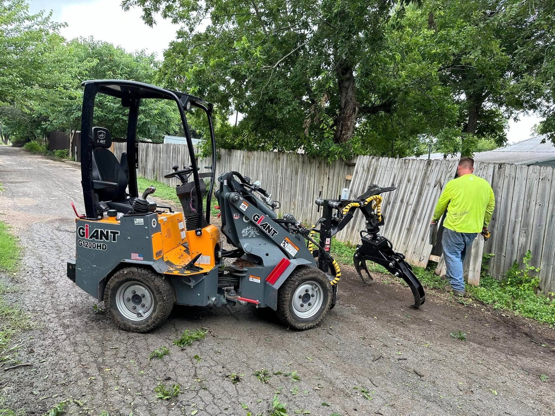 A man is standing next to a small tractor on a dirt road.