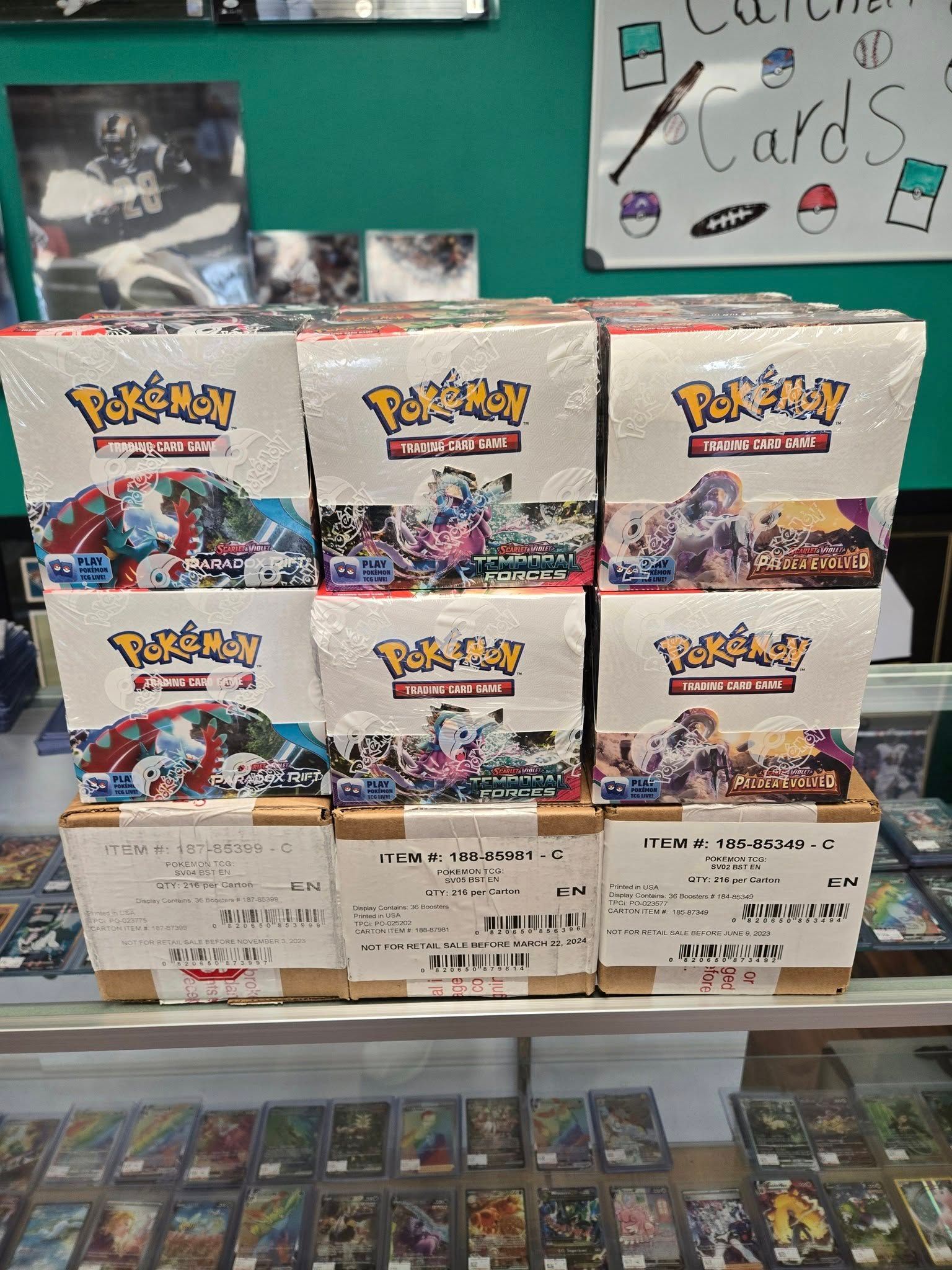 A bunch of boxes of pokemon cards are stacked on top of each other on a shelf.
