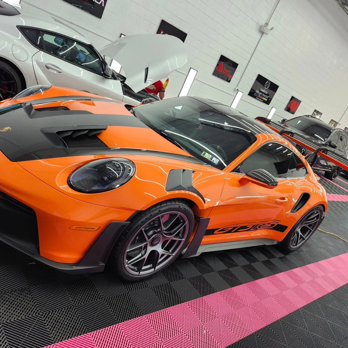 Bright orange Porsche sports car with black accents parked inside a garage.