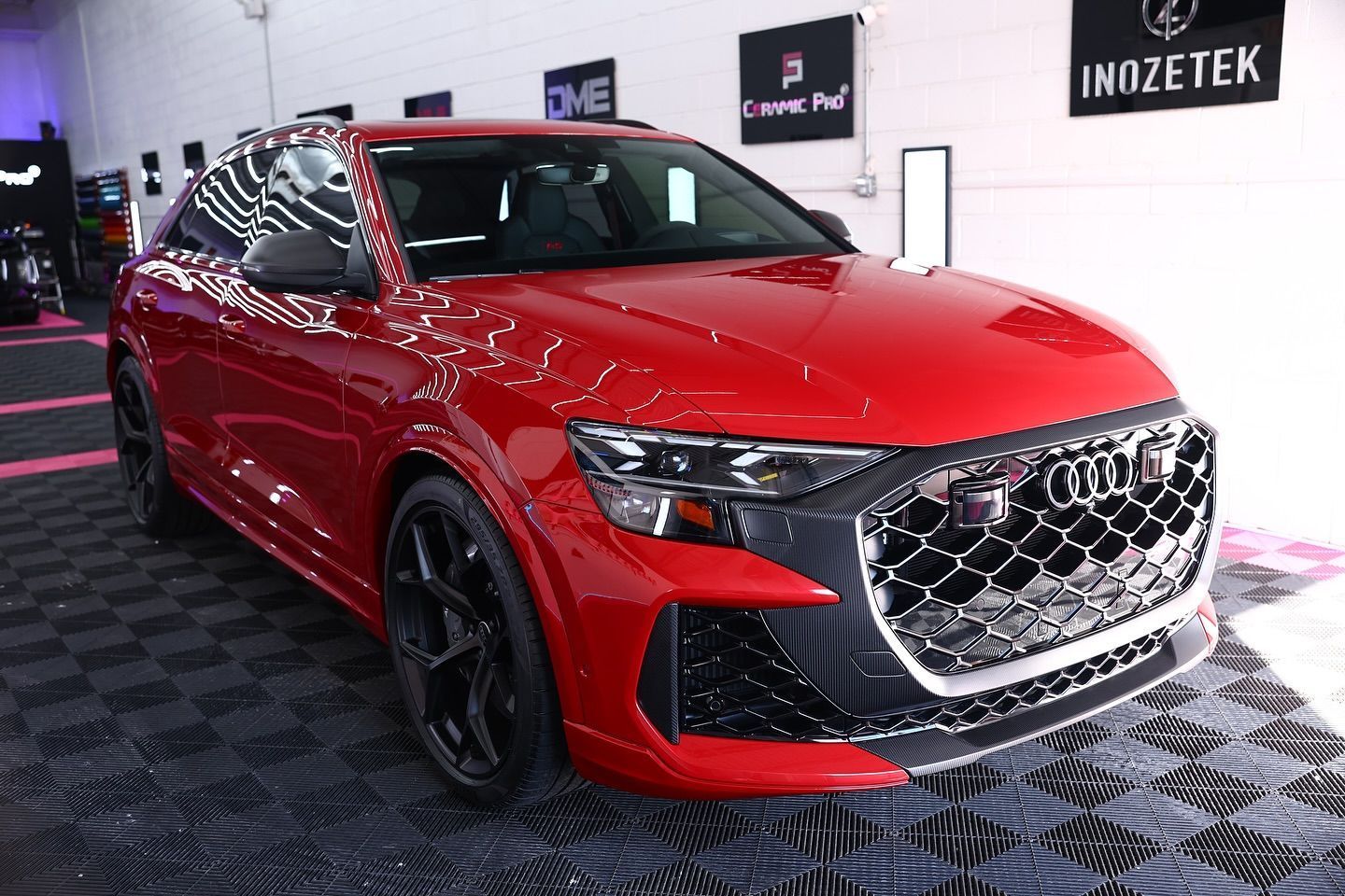 Red Audi Q8 SUV parked indoors, front view. Black wheels and trim, chrome grille.