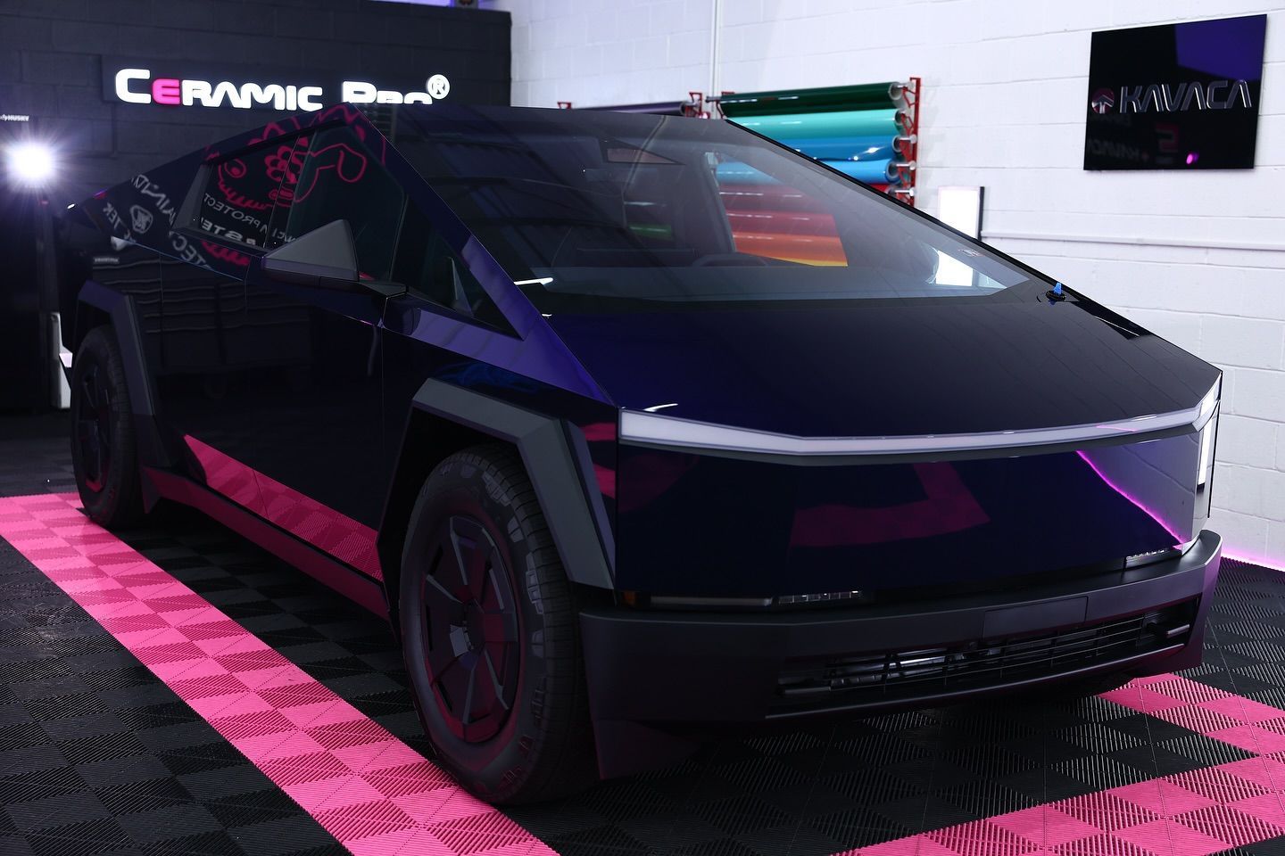 Tesla Cybertruck with purple accents, parked on a pink and black checkered floor.