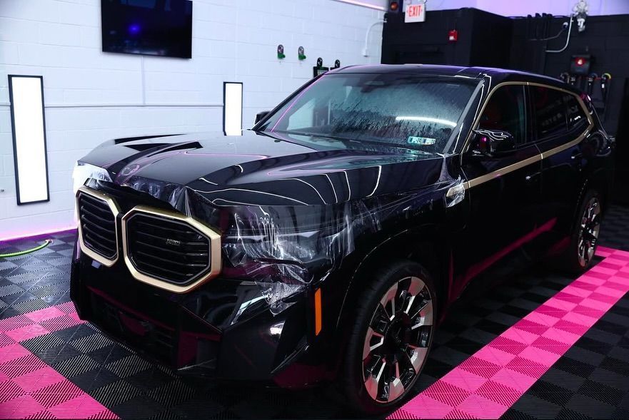 Black BMW XM SUV in a garage, showcasing gold trim.