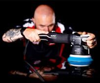 A man is polishing a car with a machine.