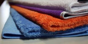 A pile of towels of different colors are stacked on top of each other on a table.