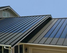 A house with a metal roof and a blue sky in the background.