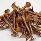 A pile of wooden screws on a white surface.