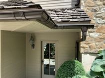 A house with a gutter on the side of it and a door.